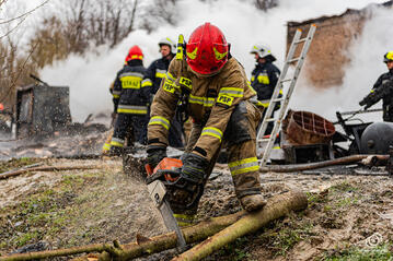 Strażak tnie drzewo podczas pożaru hali w Ołpinach